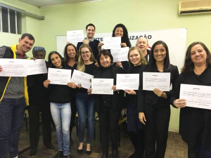 Adriana e os colegas de classe exibem seus certificados do nível básico